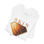 Folded white Skin Girl™ shirt displaying the bronze and gold shield logo associated with skincare confidence and barrier protection.
