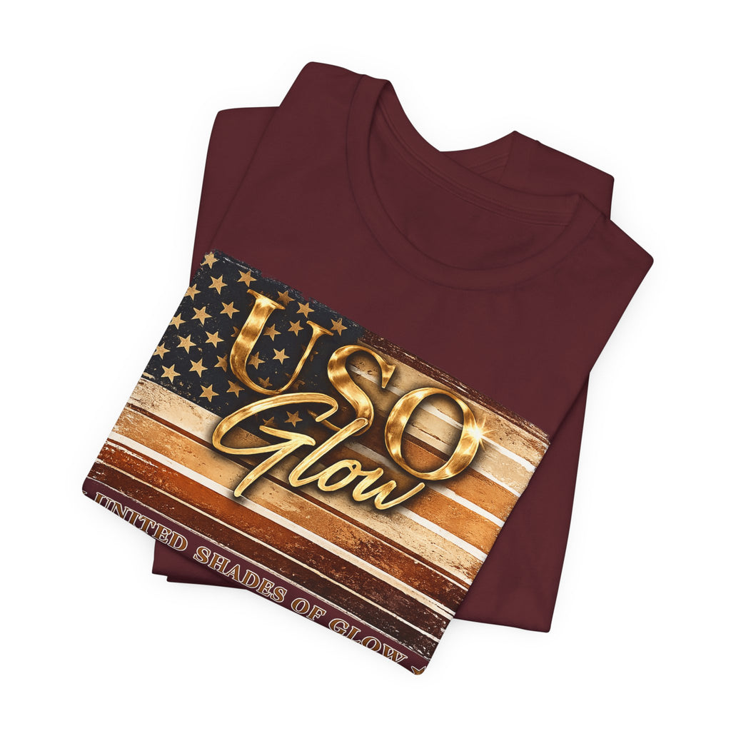 Folded burgundy graphic t-shirt showcasing the United Shades of Glow™ design in metallic-inspired colors.