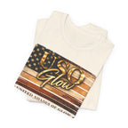 Folded cream t-shirt displaying the United Shades of Glow™ graphic in warm bronze, gold, and copper tones.