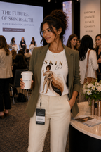 Woman wearing Skin Girl Fitz 4 Resilient esthetician graphic t-shirt at beauty show with tea in hand